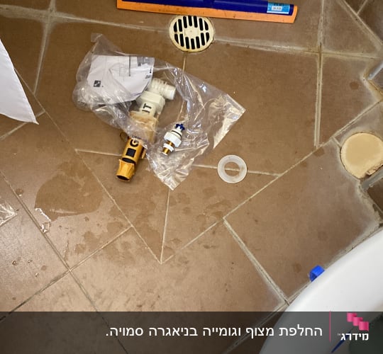 כלים וחלקים לעבודת אינסטלציה על רצפת חדר אמבטיה